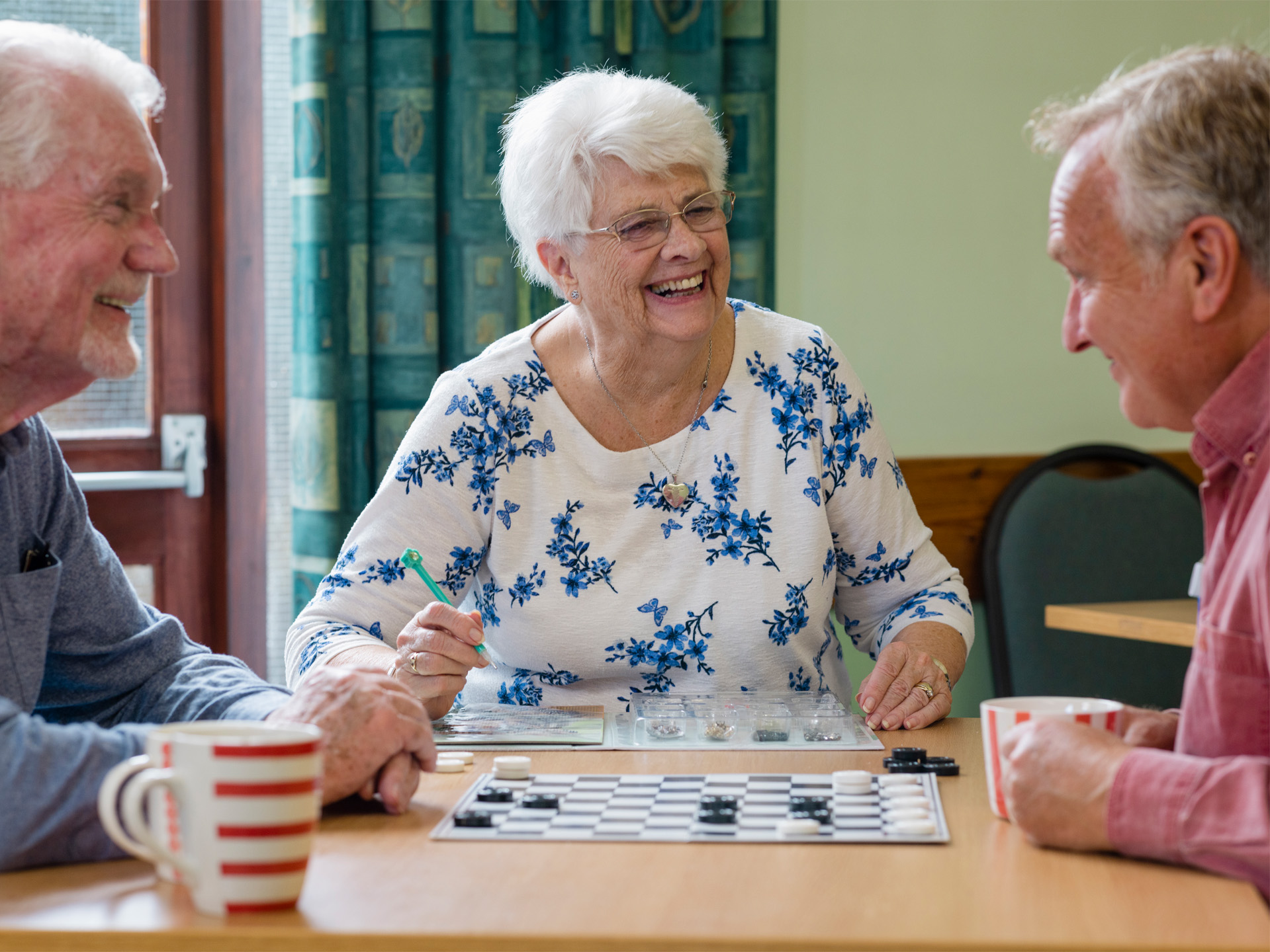 Drei Patienten spielen Mühle und lachen